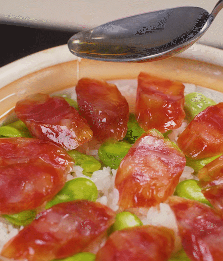 大米出現(xiàn)小孔時(shí)開蓋放香腸，往鍋邊淋入少許油，再燜煮8~10分鐘左右。